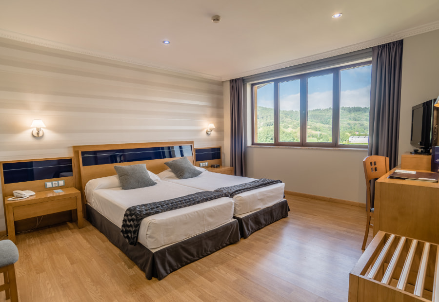 Habitación doble 1 Room with two single beds, television and exterior views.